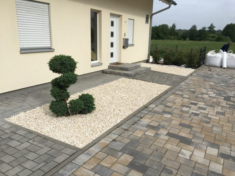 Modern gestalteter Vorgarten mit Pflaster und weißem Zierkies